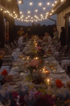 a long table is set up with flowers and candles for an outdoor dinner or party