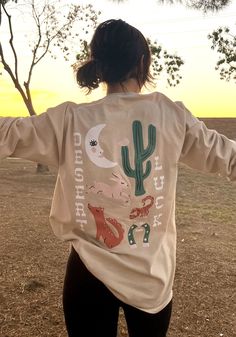 Luck is hard to come by in the southwest, but when karma blows its dusty fortune your way you better hang on! Get lucky with this retro inspired tee, featuring hand drawn graphics and vibrant, screen print ink. Unisex long sleeve t-shirt in Sand. 100% cotton. Blonde model wears size X-Small.Brunette model wears size X-Large. Cowgirl T Shirt, Cowgirl Tshirt, Western Graphic Tees, Brunette Models, Country Music Shirts, Cowgirl Shirts, Mama Tee, Blonde Model, Cow Girl