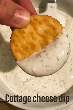 a person dipping cheese on top of crackers in a white bowl with dip sauce