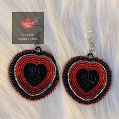 red and black beaded heart shaped earrings on white furnishing with canadian creative space logo