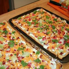 two pizzas sitting on top of pans covered in cheese and veggies