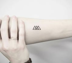 a woman's arm with a small triangle tattoo on the left side of her arm