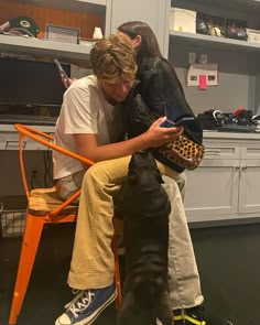 two people sitting on a chair with a dog