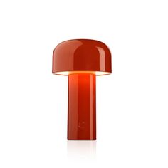 an orange table lamp on a white surface with the light turned on and dimming