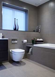 a white toilet sitting next to a bath tub in a bathroom under a window above a sink