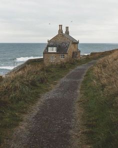 an old house on the side of a cliff by the ocean