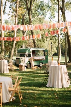 a food truck parked in the middle of a park with tables and chairs set up