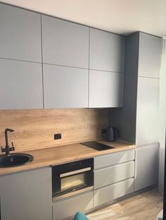 a kitchen with white cabinets and wood counter tops