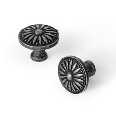 two black knobs with an intricate design on them, one in the shape of a flower