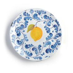 a blue and white plate with an orange on it's side, sitting on a white surface