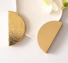 a white plate topped with a piece of cake next to a gold slice on top of it