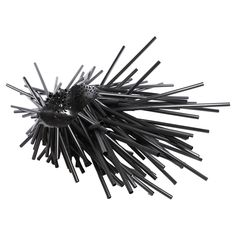 a close up of a black object on a white surface with lots of sticks sticking out of it