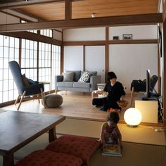 two people sitting on the floor in a room with wood paneling and large windows