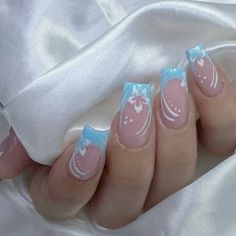 a woman's hand with pink and blue nail polish on it, holding onto a white