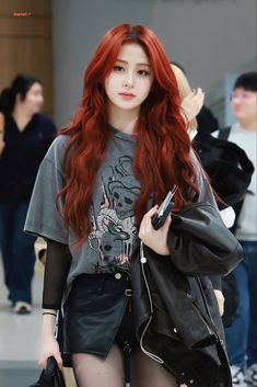 a woman with long red hair and black tights holding a cell phone in her hand