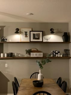 a dining room table with chairs and shelves above it