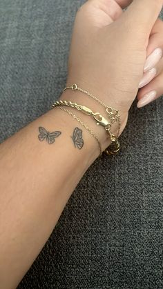 a woman's arm with three butterfly tattoos on it and two chain bracelets