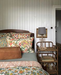 a bed with floral sheets and pillows in a bedroom next to a lamp on an end table