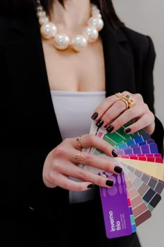 a woman in a black suit holding a card and some rings