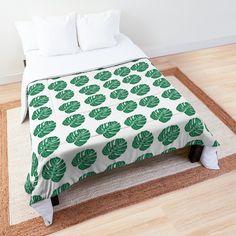 a bed with green leaves on it in a room next to a rug and pillows