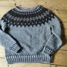 a gray sweater sitting on top of a wooden floor