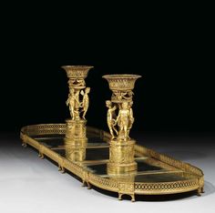 two golden vases sitting on top of a glass table