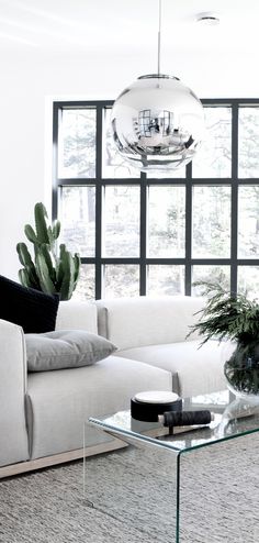 a living room filled with white furniture and lots of glass table top on top of it