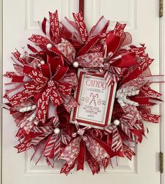 a red and white christmas wreath hanging on a door