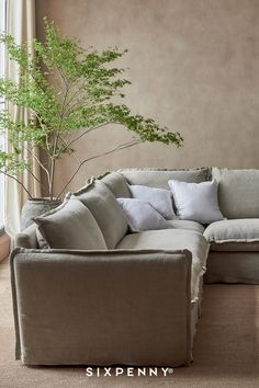 a living room with a large sectional couch and a potted plant in the corner