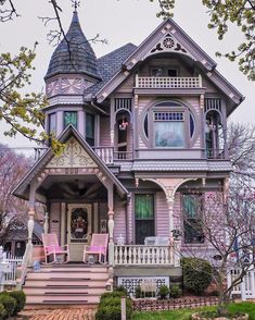 an old victorian house with pink chairs on the front porch and steps leading up to it