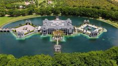 an aerial view of a large mansion in the middle of a lake surrounded by trees