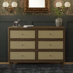 a dresser with drawers in front of a mirror and lamp on the wall above it