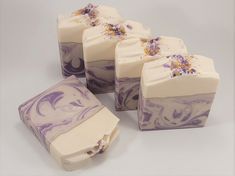 four soap bars with purple and white designs on them, sitting next to each other