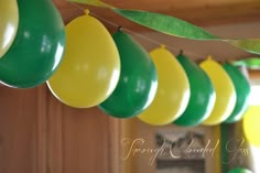 green and yellow balloons are hanging from the ceiling