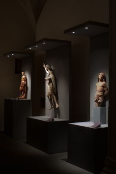 some statues are on display in a dark room