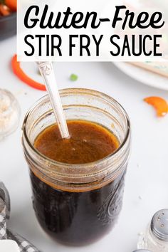 a jar filled with stir fry sauce sitting on top of a table next to other food