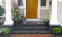 a front porch with potted plants on the steps