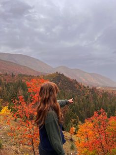 a woman pointing out at the mountains in autumn