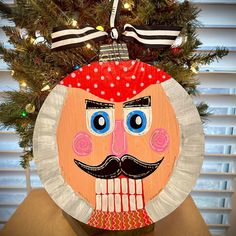 a paper plate christmas ornament with a man's face on top of it