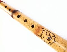 a close up of a wooden flute with an animal on it's side and four holes in the middle