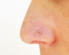 a woman's nose with a small heart shaped earring on top of it