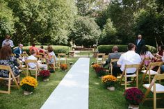 an outdoor ceremony with people sitting in chairs and flowers on the aisle leading up to the aisle