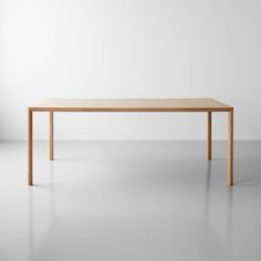 a wooden table sitting on top of a white floor next to a wall in an empty room