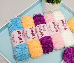 several skeins of yarn sitting on a tray next to a potted plant