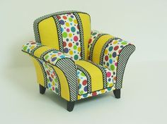 a yellow chair with colorful polka dots on the back and arms, sitting in front of a white background