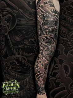 a man with tattoos on his arm and leg is standing in front of a black background