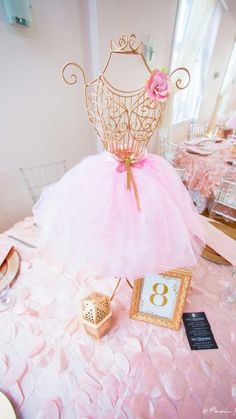 a pink dress sitting on top of a table next to a clock and other items