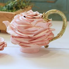 a pink tea pot and two cups on a table