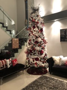 a white christmas tree with red and silver ornaments in a living room next to stairs