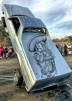 an old car with a drawing on it's side parked in a parking lot